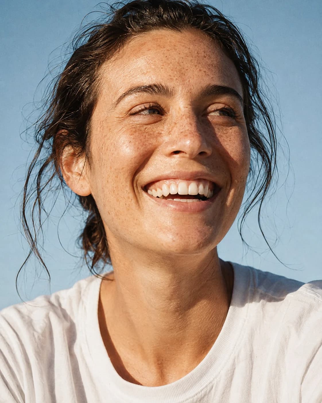 A woman with freckles smiling naturally in warm afternoon sunshine
