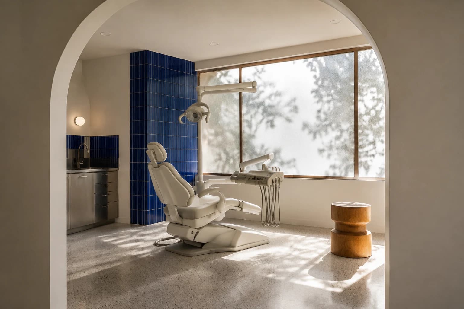 A bright dental suite with a cobalt tiled wall and soft natural light