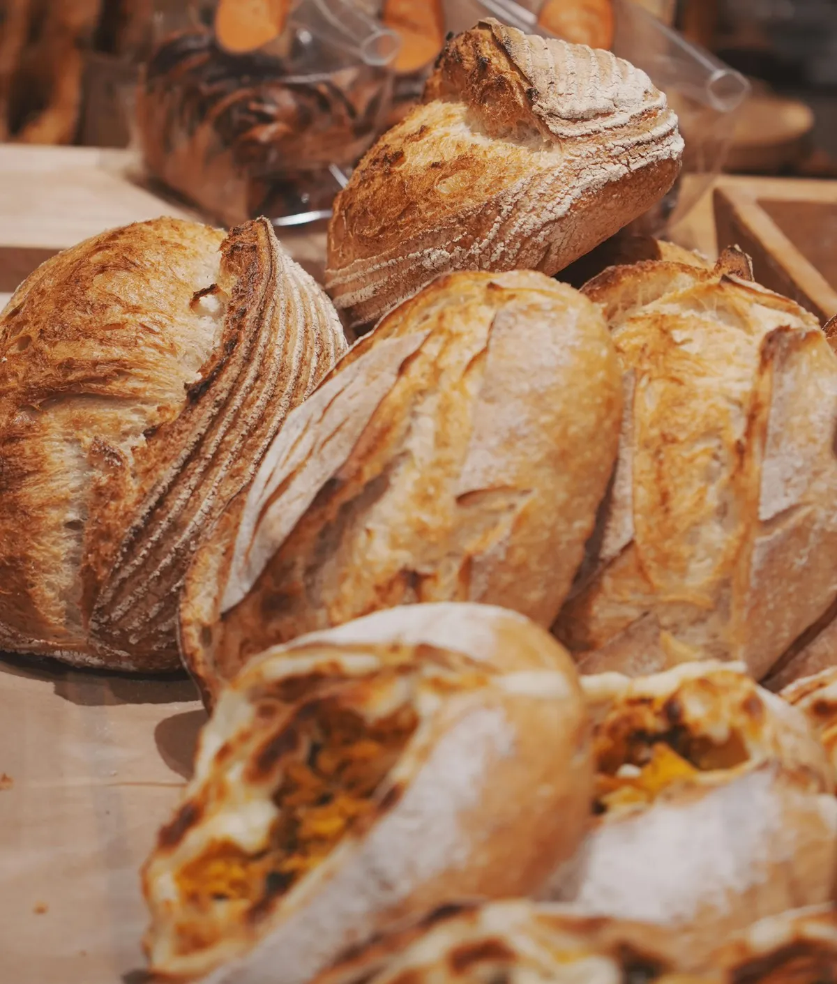 A counter piled with scored, flour-dusted sourdough loaves
